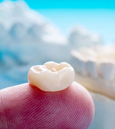 A close-up of a finger holding dental crowns in Dayton