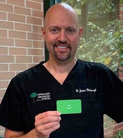 Dentist who provides dental implant tooth replacement holding up his card