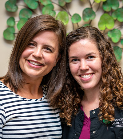 Two dental implant team members smiling