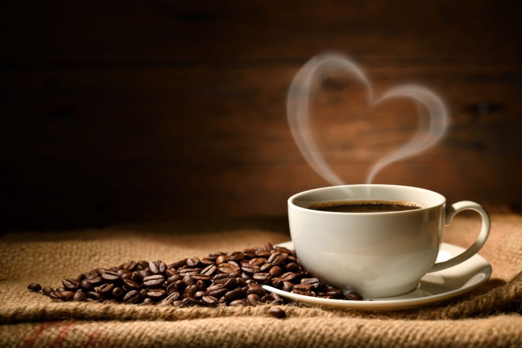 Cup of coffee on a brown cloth with the steam creating a heart