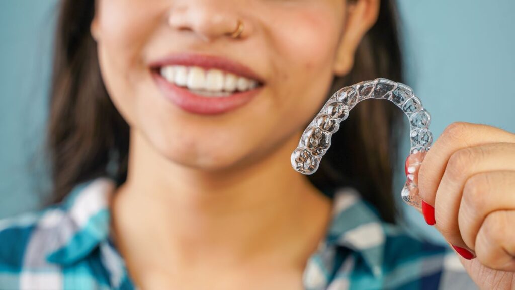 A woman holding an Invisalign aligner